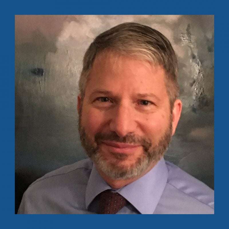 Bearded man with gray hair smiling and looking into the camera