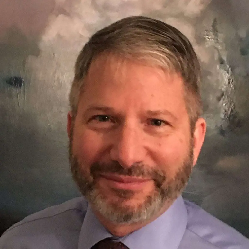 Bearded man with gray hair smiling and looking into the camera