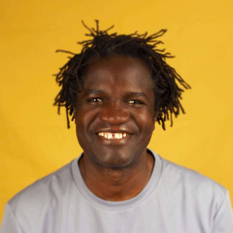 Boucar Diouf en chandail pâle, sur fond jaune moutarde